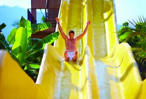 excited man having fun on water slide in tropical aqua park