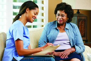 Nurse Making Notes During Home Visit With Senior Female Patient