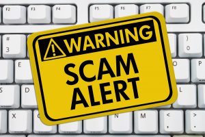 Computer keyboard keys with warning sign with words Scam Alert, Scam Alert