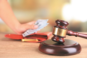 Gavel and hand holding money in wallet on wooden background